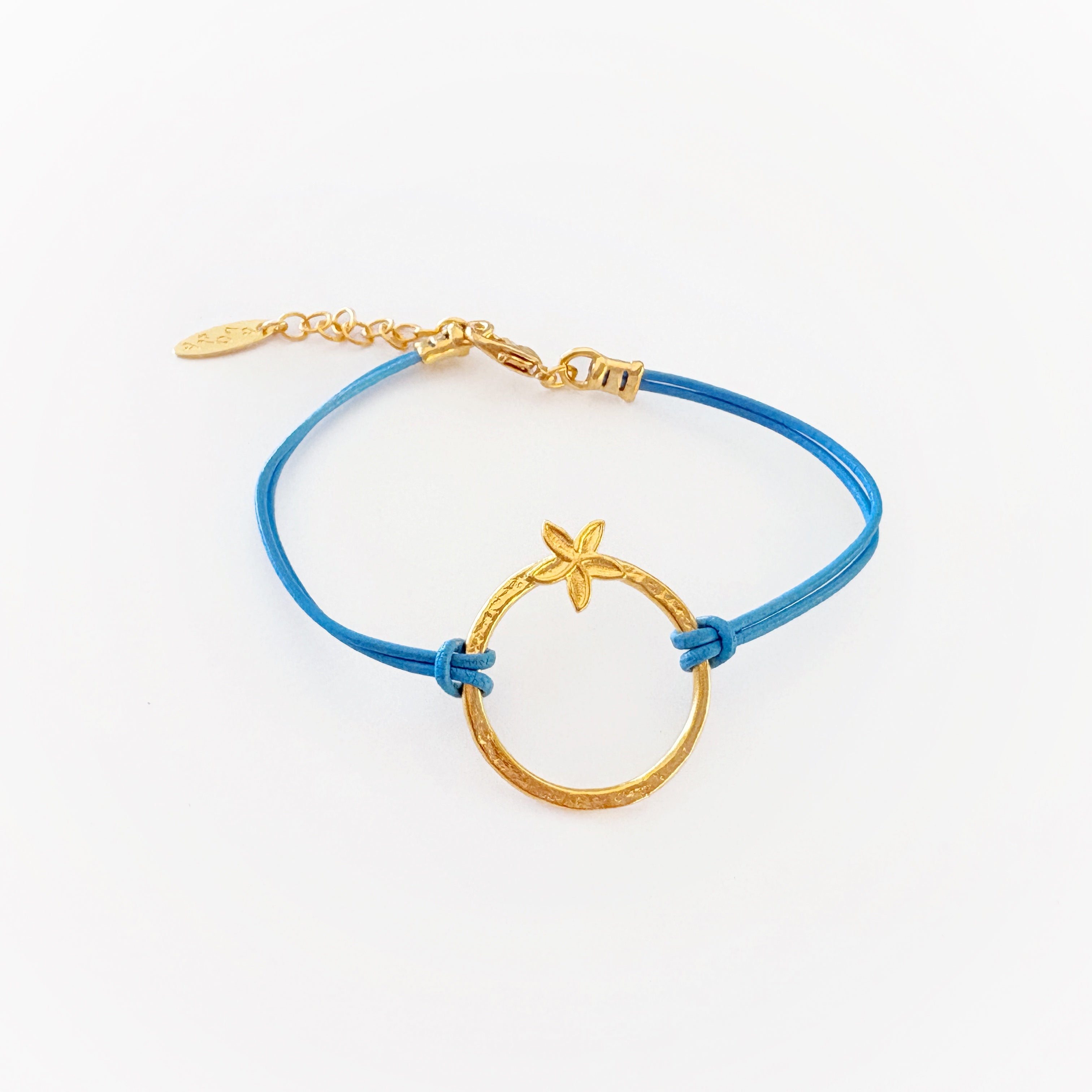 Blue flower bracelet with a gold clasp on a white background. blue leather. gold plumeria