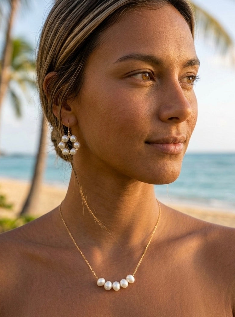 Woman wearing pearl earrings and necklace on a beach