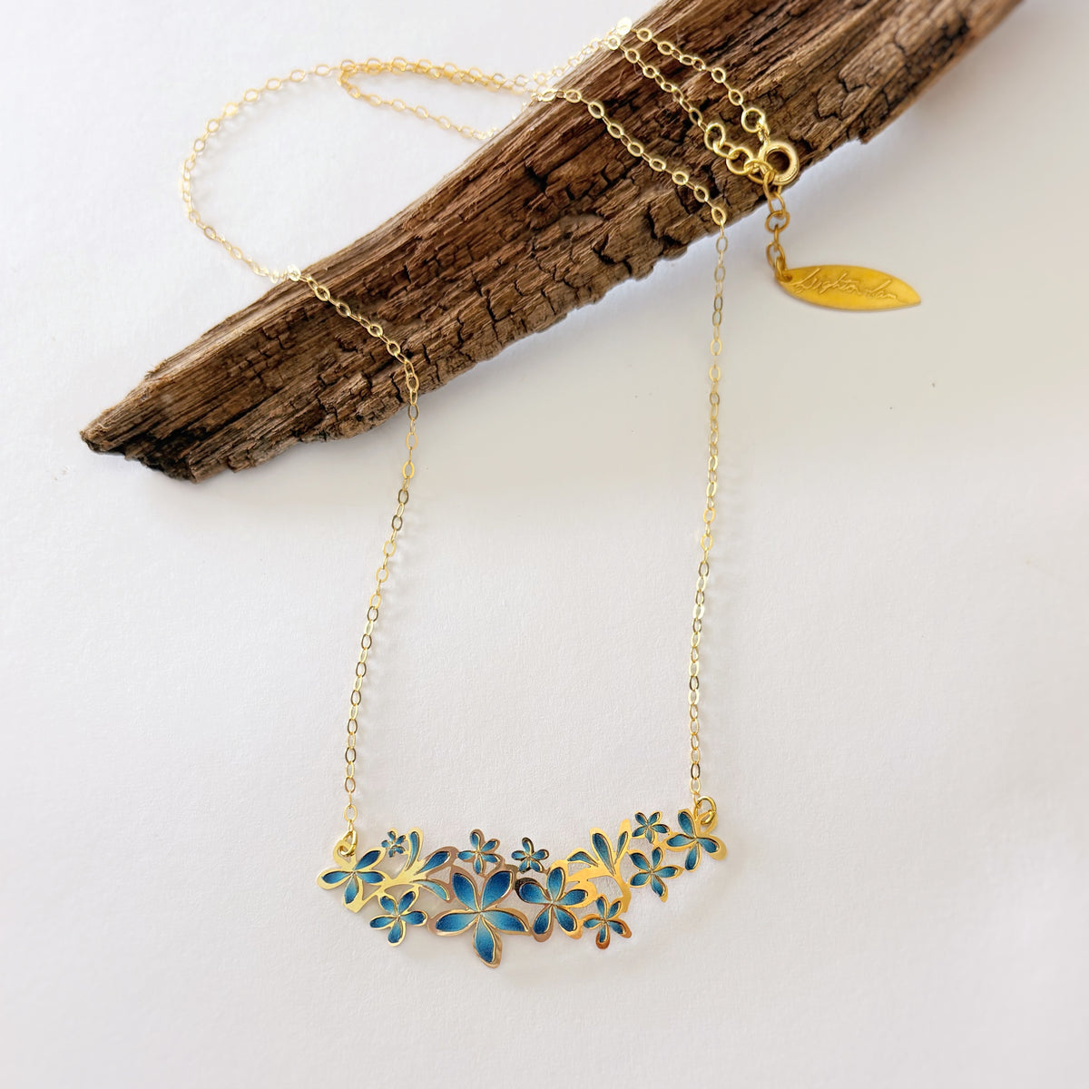 Gold necklace with floral design on a white background. plumeria lei